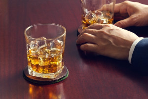 Whiskey on wooden table and businessman with whiskey in hand
