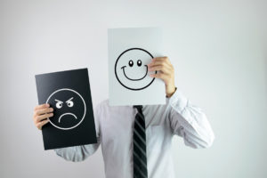 Businessman holding two papers with happy and angry face each on them